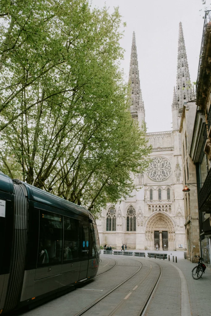 A modern tram gliding by the historic Bordeaux Cathedral in an urban street scene.